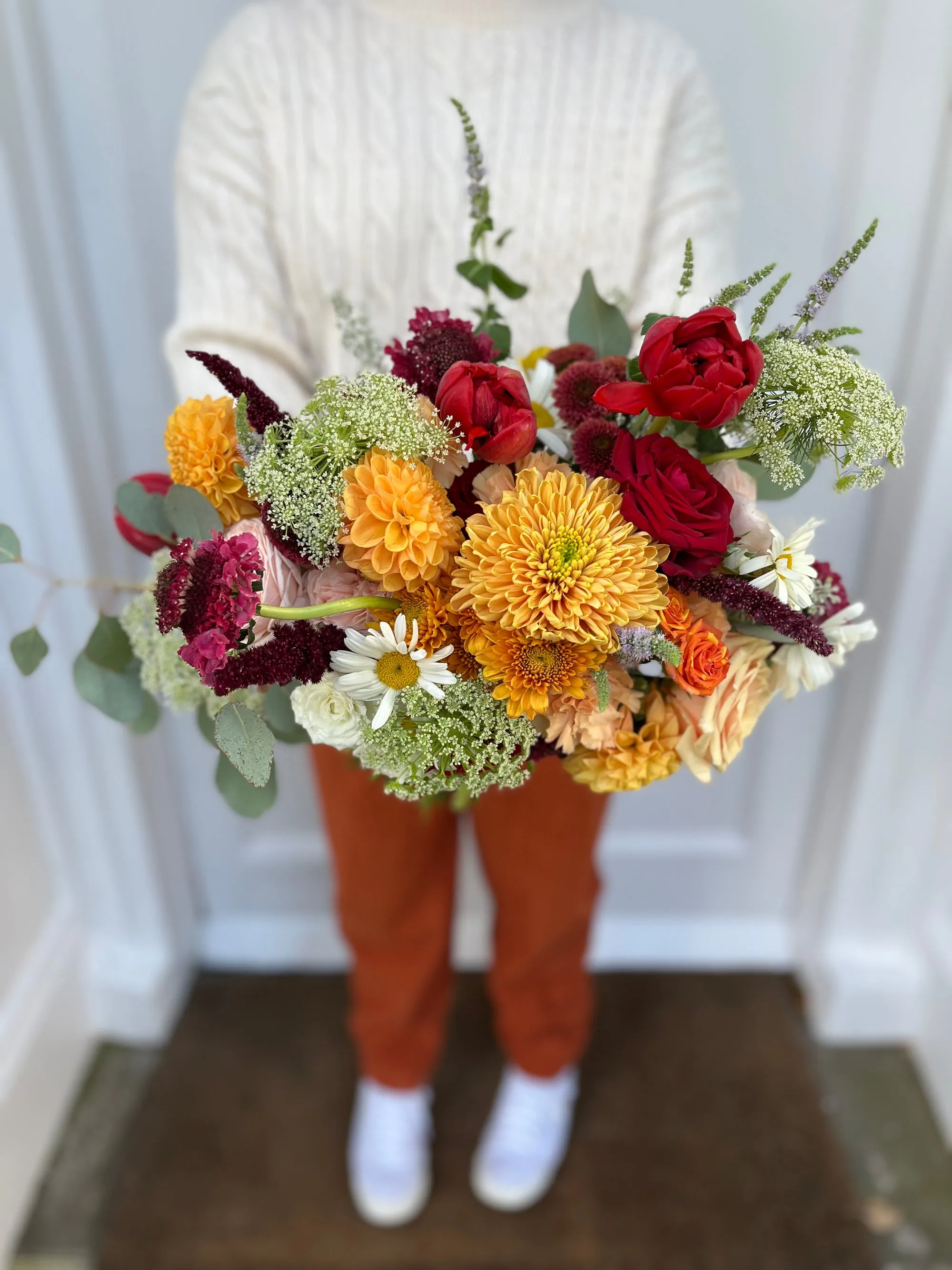A hand tied bouquet in burgundy and mustard