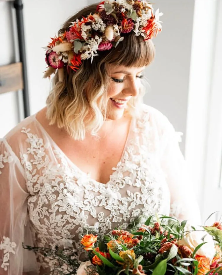 A bride in a flower crown holding a coral bouquet