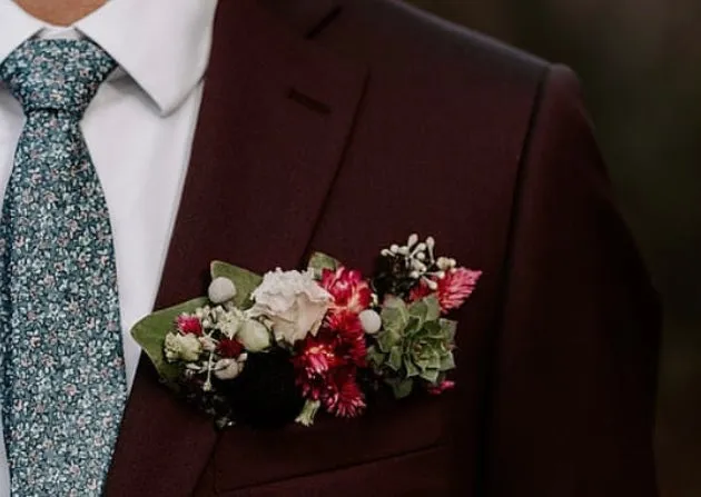 A buttonhole pinned to a burgundy suit