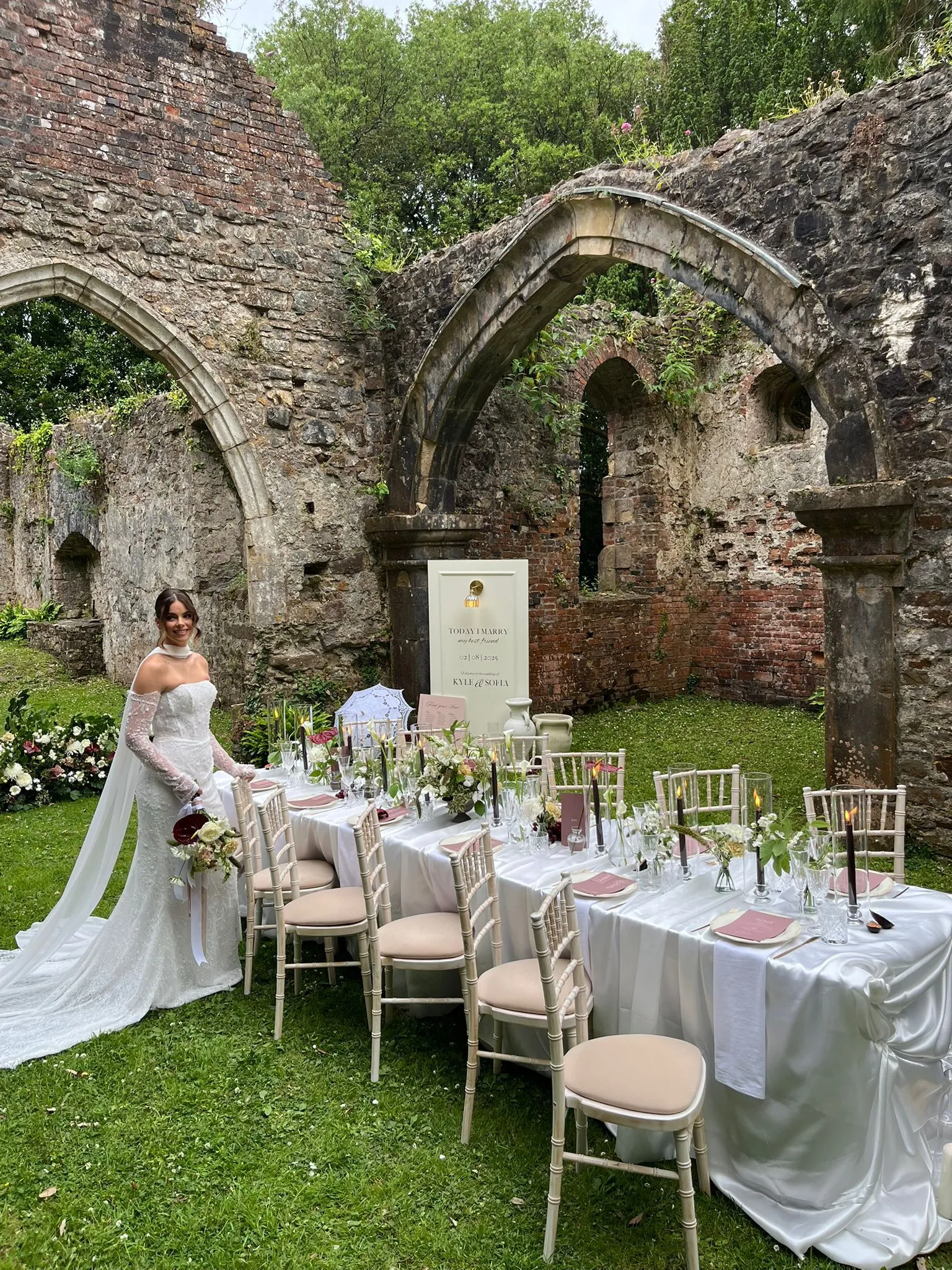 A long table dressed with greenery inside stone ruins