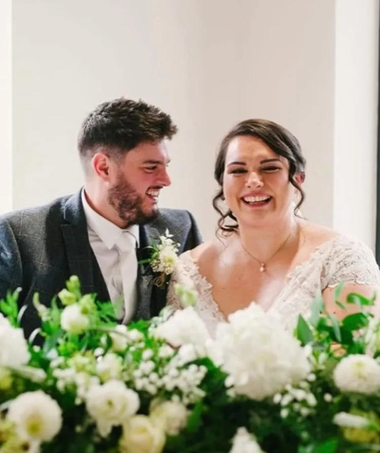 A couple behind a top table of white and green flowers